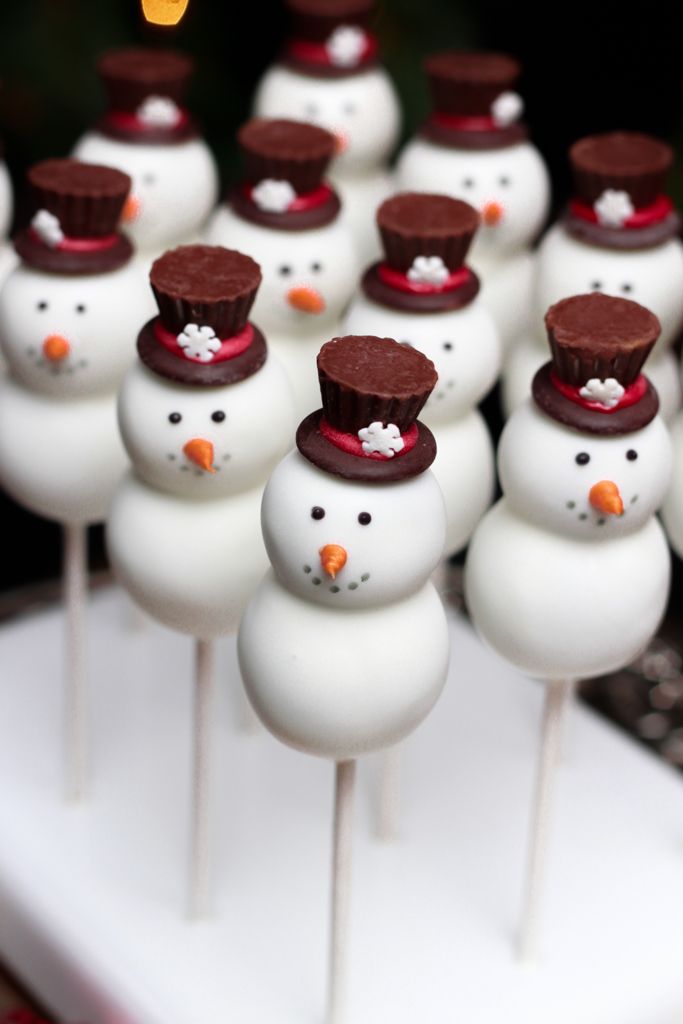 chocolate covered marshmallows with hats and snowmen on them sitting on a white tray