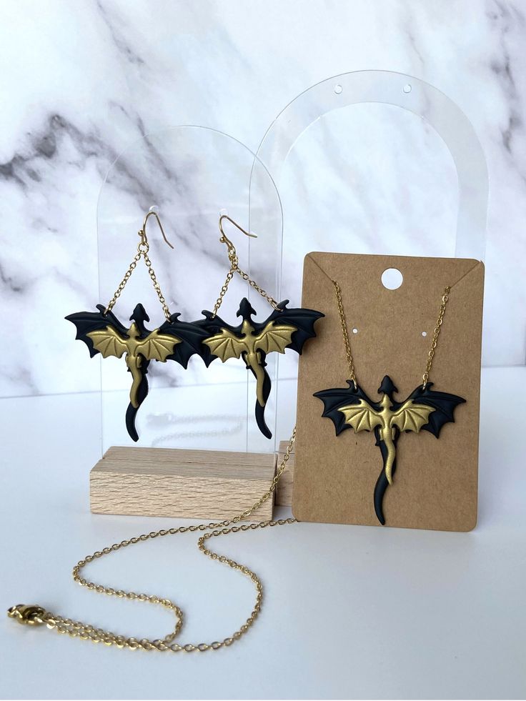 These handmade dragon earrings are one of a kind! They are lightweight and comfortable to wear all day long! All metal in earrings and necklace are surgical stainless steel so they are tarnish resistant and hypoallergenic. Care Instructions: Try not to excessively bend or stress earrings. Don't sleep, swim, work out, etc. while wearing them. Handmade in Kansas :) Black Jewelry For Halloween Fantasy Events, Gold Metal Jewelry For Cosplay, Gothic Gold Jewelry For Cosplay, Black Metal Jewelry For Fantasy Events, Themed Black Dangle Jewelry, Themed Black Metal Jewelry, Handmade Black Jewelry For Cosplay, Handmade Gold Jewelry For Cosplay, Nickel Free Themed Black Jewelry