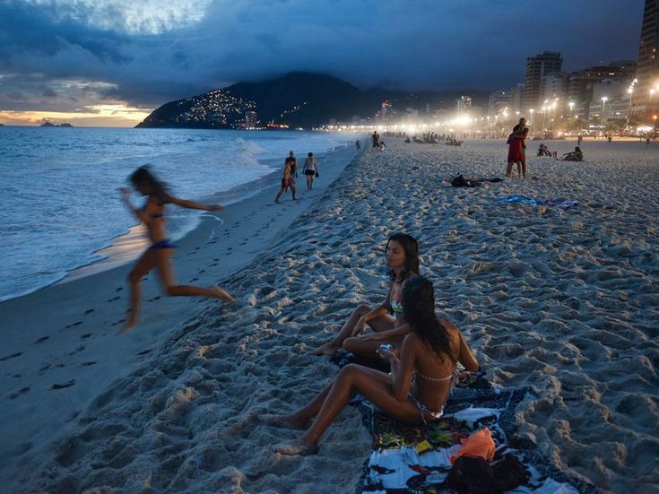 some people are sitting on the beach at night