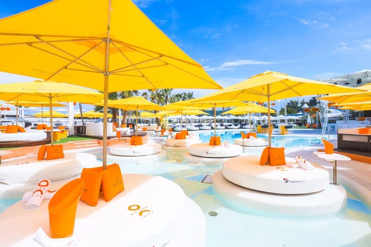 an outdoor pool with yellow umbrellas and lounge chairs