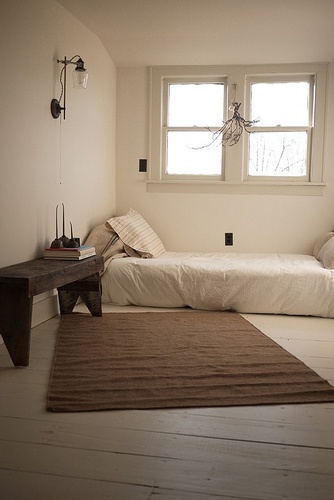 a room with two beds and a rug on the floor in front of a window