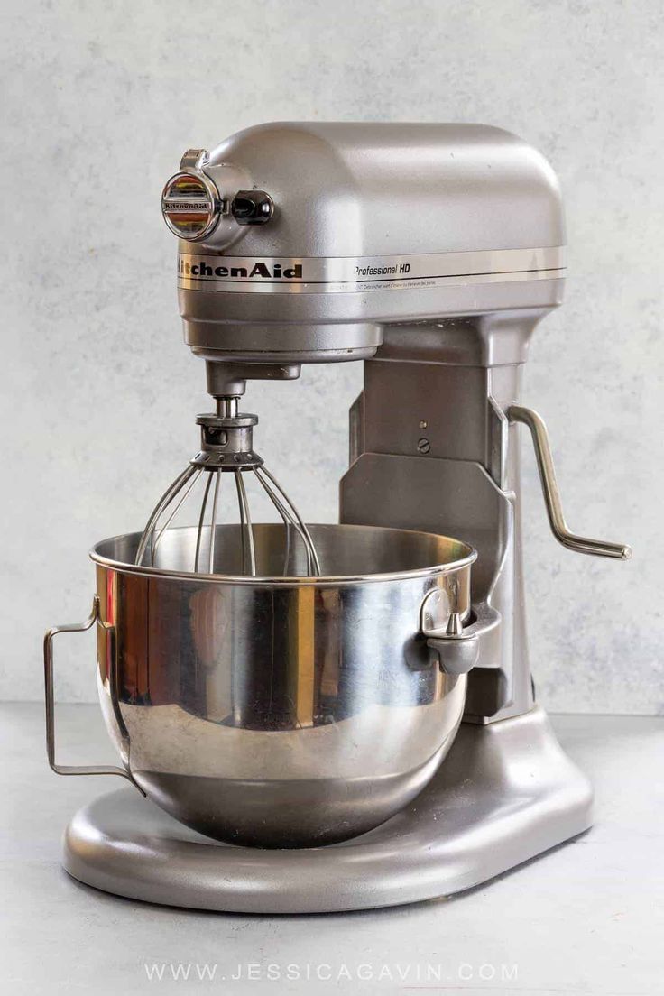 a silver mixer sitting on top of a metal stand next to a white countertop