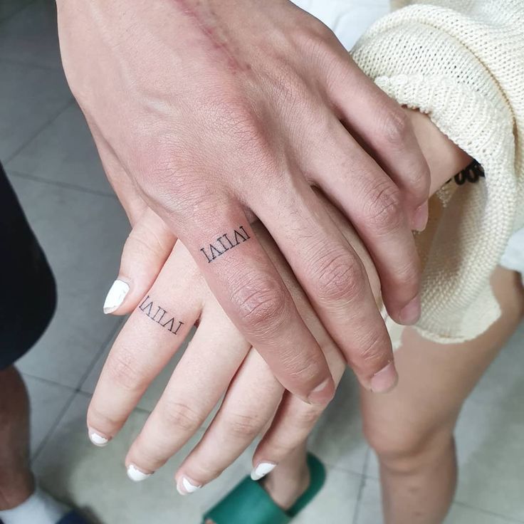 two people holding hands with tattoos on their fingers and the words italia written on them