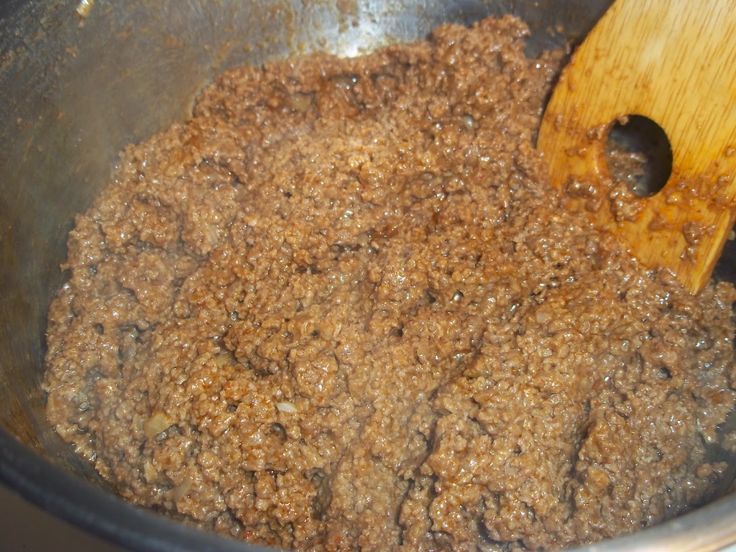 a wooden spoon in a metal bowl filled with brown sugar and ground cinnamon flakes