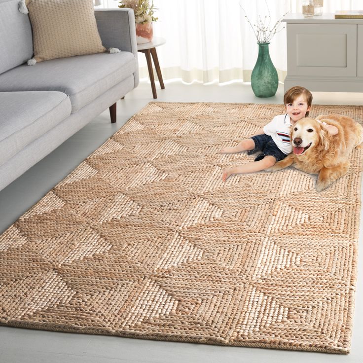 a little boy sitting on the floor next to a brown dog in front of a couch