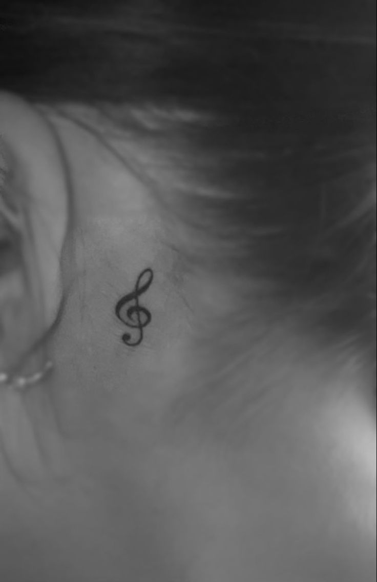 a woman's ear with a small treble tattoo on it