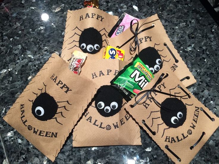 three halloween bags with googly eyes and candy on them sitting on a granite counter top