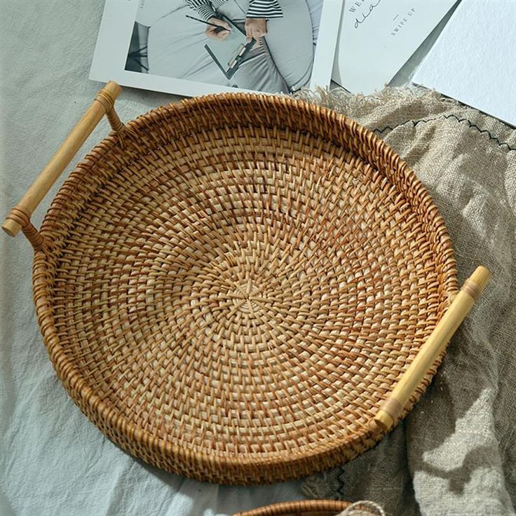 a wicker basket sitting on top of a bed next to an open book and magazine