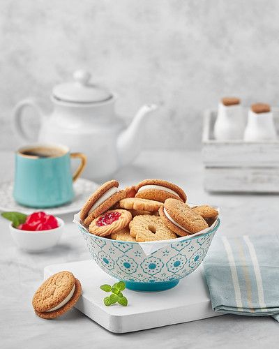 a bowl filled with cookies next to two tea cups