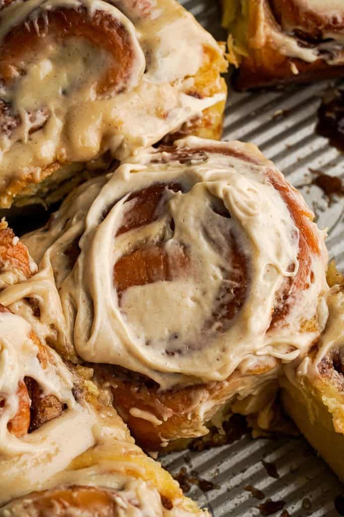 cinnamon rolls with icing sitting on top of a cooling rack