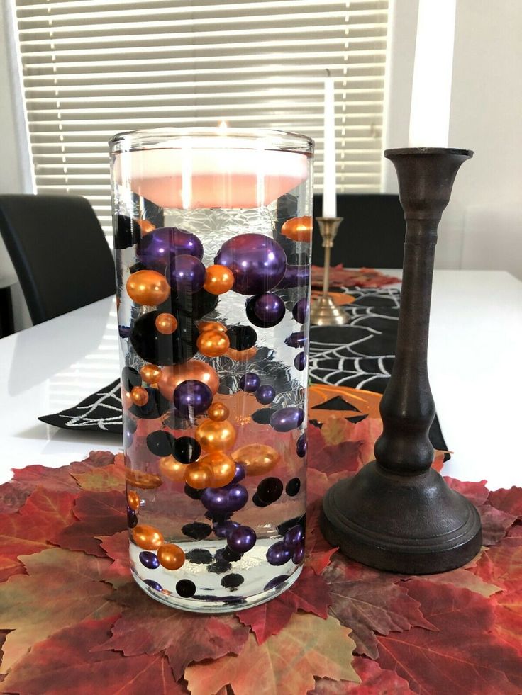 a candle is sitting on a table next to a vase with balls and candlesticks