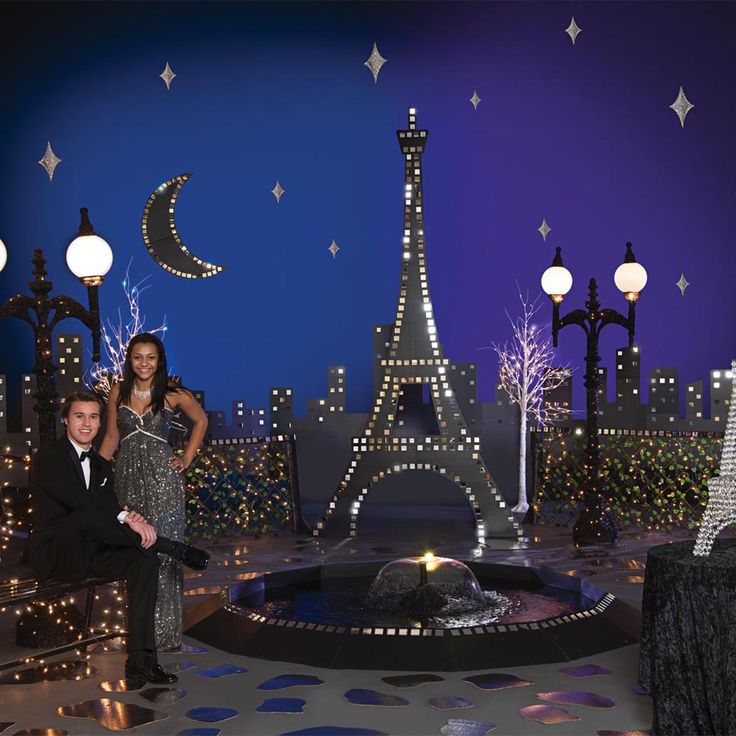 a man and woman posing in front of the eiffel tower at christmas time