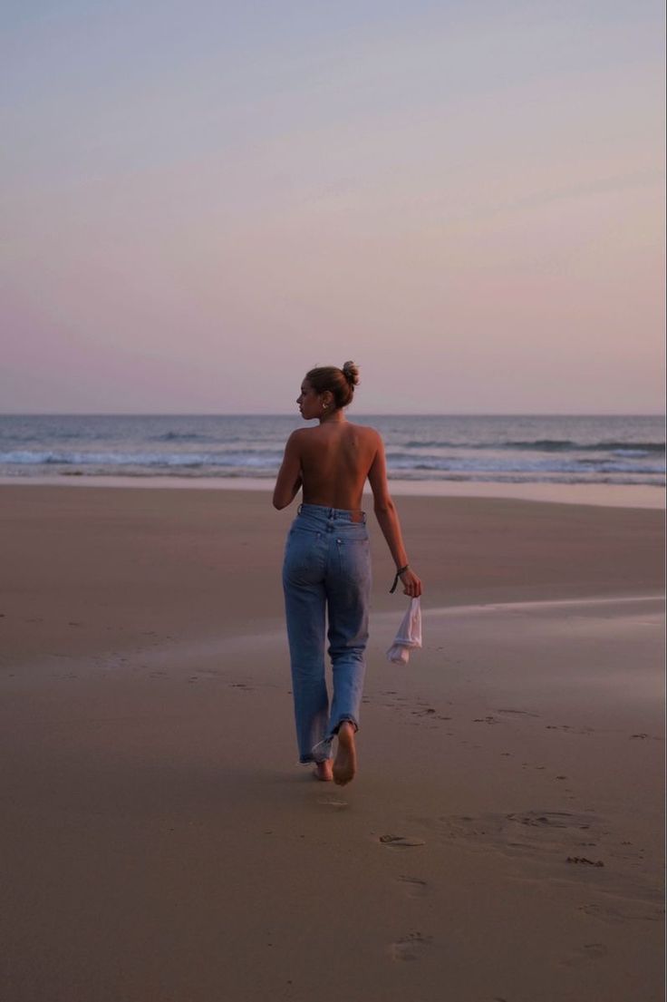 a woman walking on top of a sandy beach