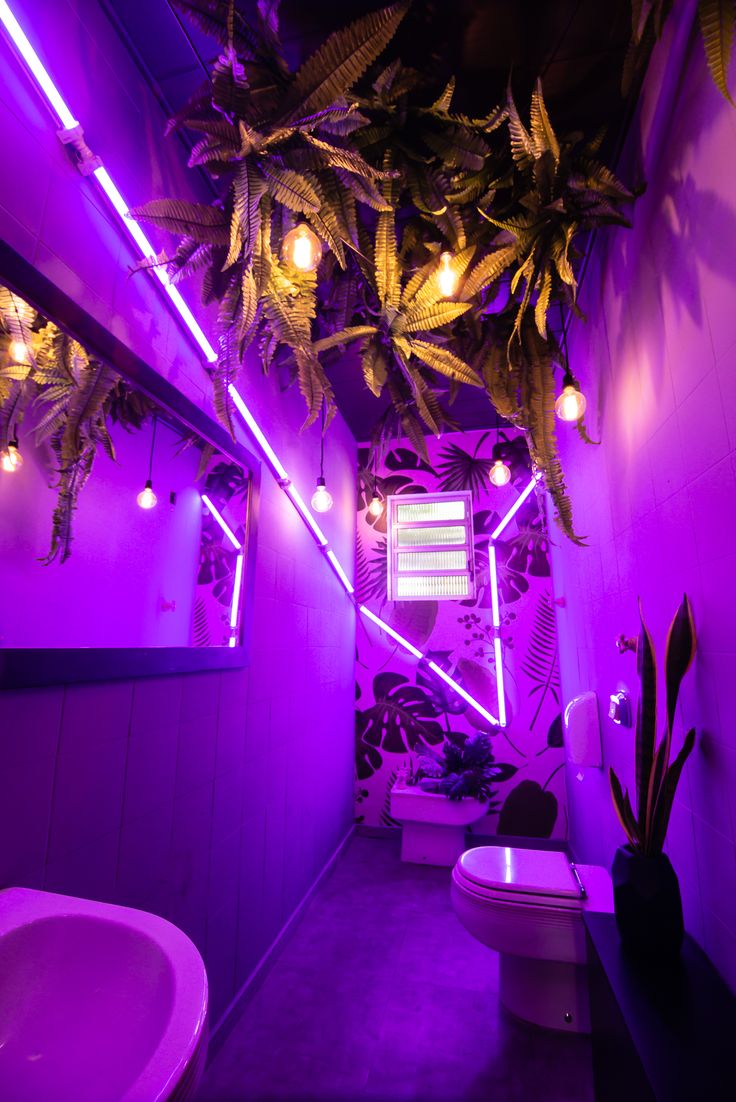 a bathroom with purple lighting and plants hanging from the ceiling