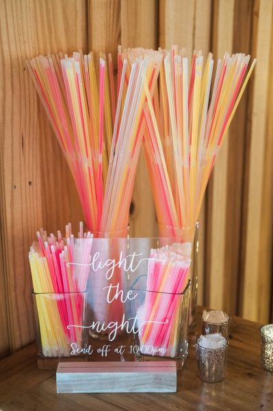 there are many different colored straws in the glass vase on the table next to each other