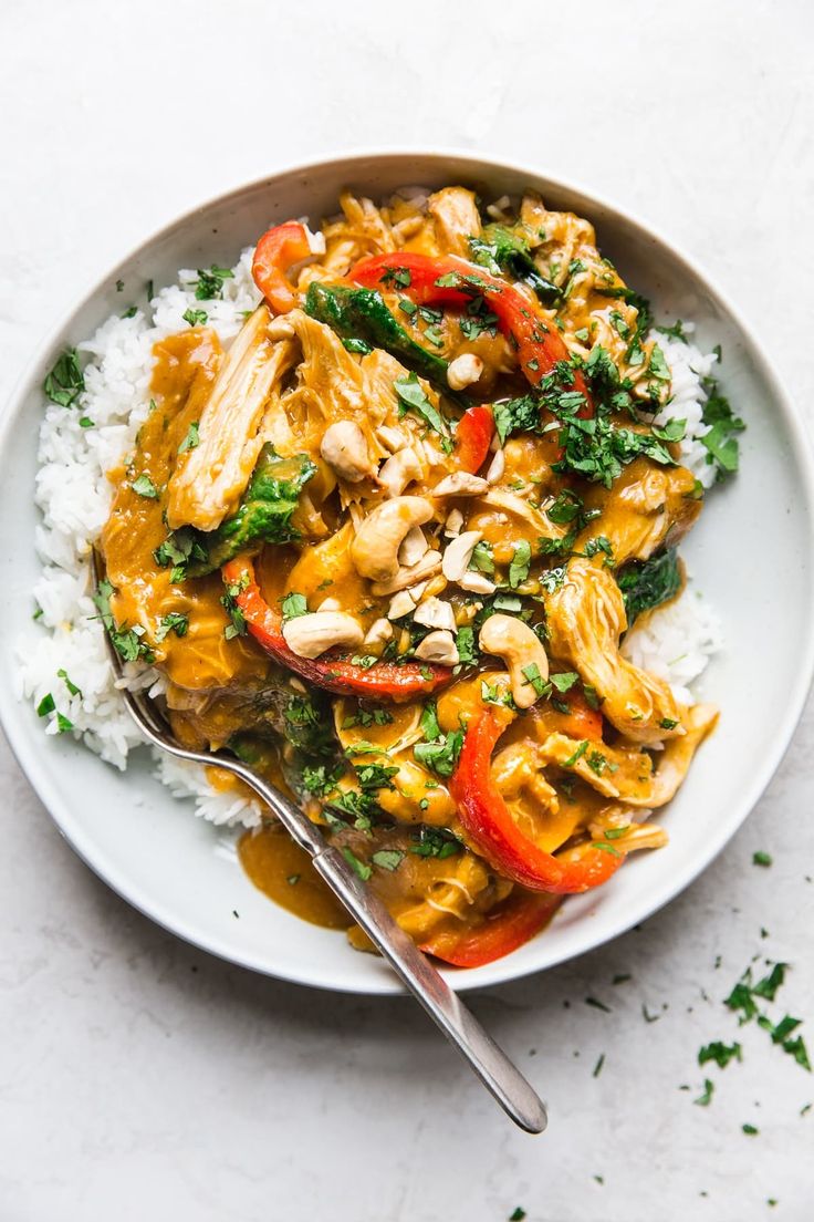 a white plate topped with chicken and veggies over rice covered in gravy