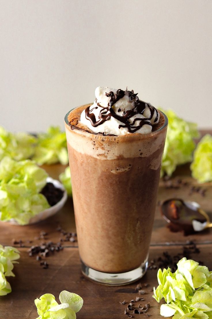 there is a drink with whipped cream and chocolate on the table next to lettuce