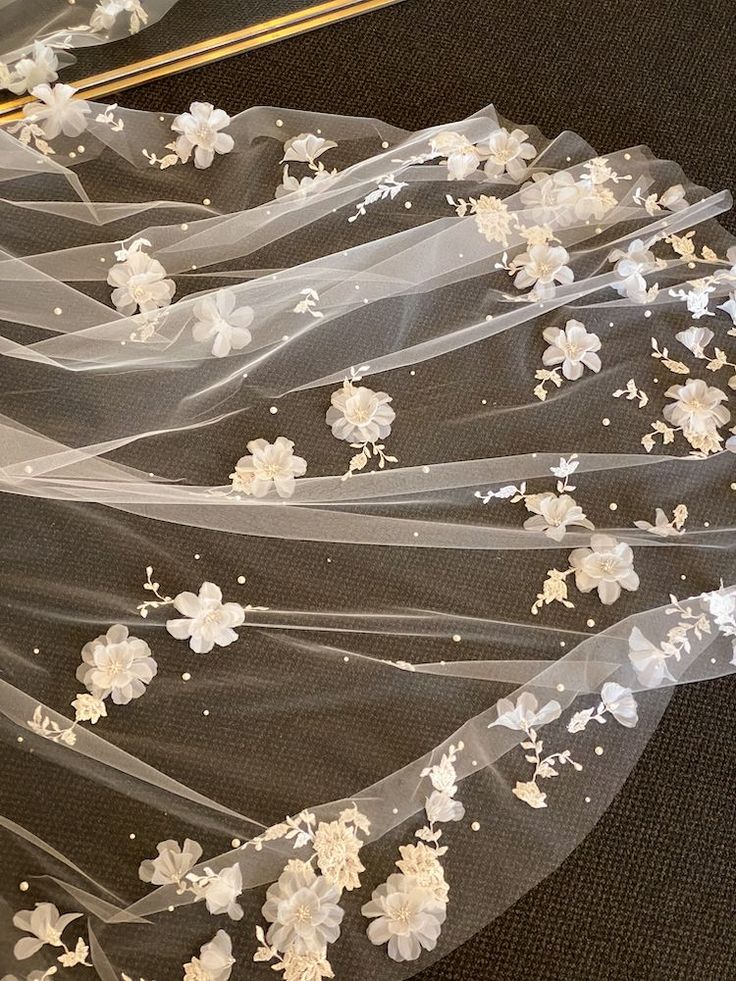 wedding veil with flowers on it laying on the floor next to a pair of scissors