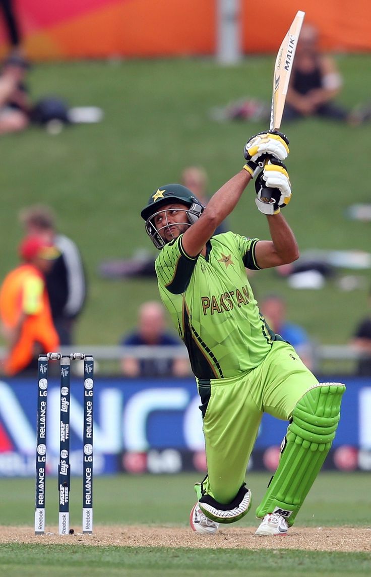 a man in green jersey playing a game of cricket