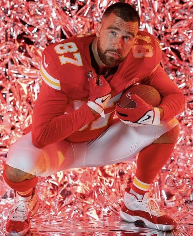 a football player kneeling down with his hands on his knees and looking at the camera