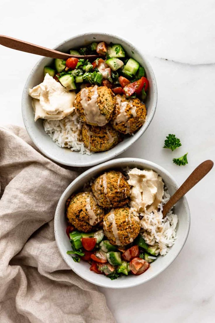 two bowls filled with meatballs, rice and vegetables