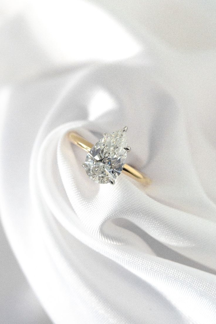 an engagement ring on top of white fabric