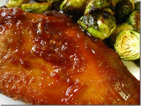 chicken with sauce and brussel sprouts on a white plate, ready to be eaten