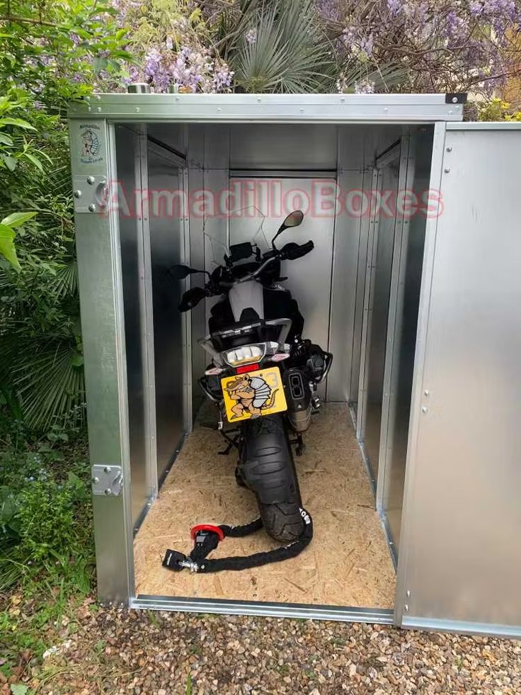 a motorcycle is parked in a small metal storage shed with the door open to it's side