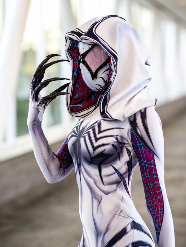 a woman dressed in spider - man costume holding her hands up