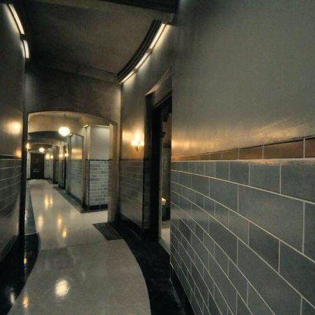 a long hallway with tile walls and lights on either side of the corridor is lit by recessed lighting