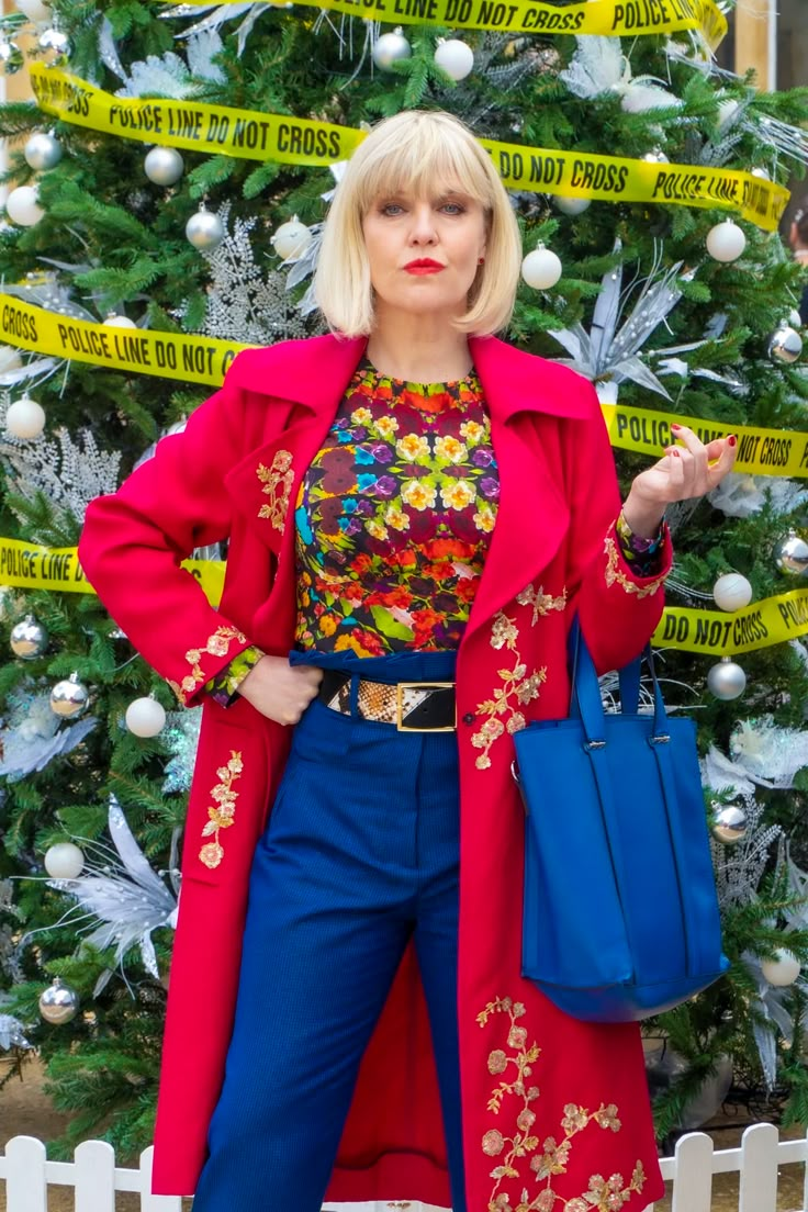 a woman standing in front of a christmas tree