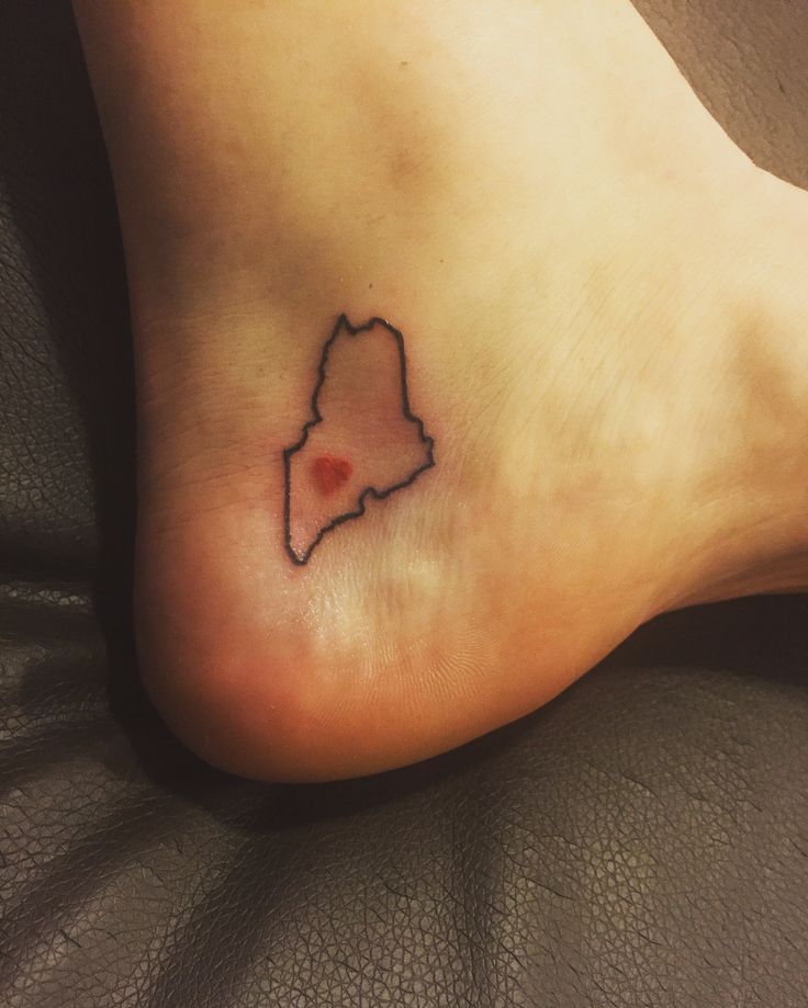 a small tattoo on the foot of a person with a red dot in the middle