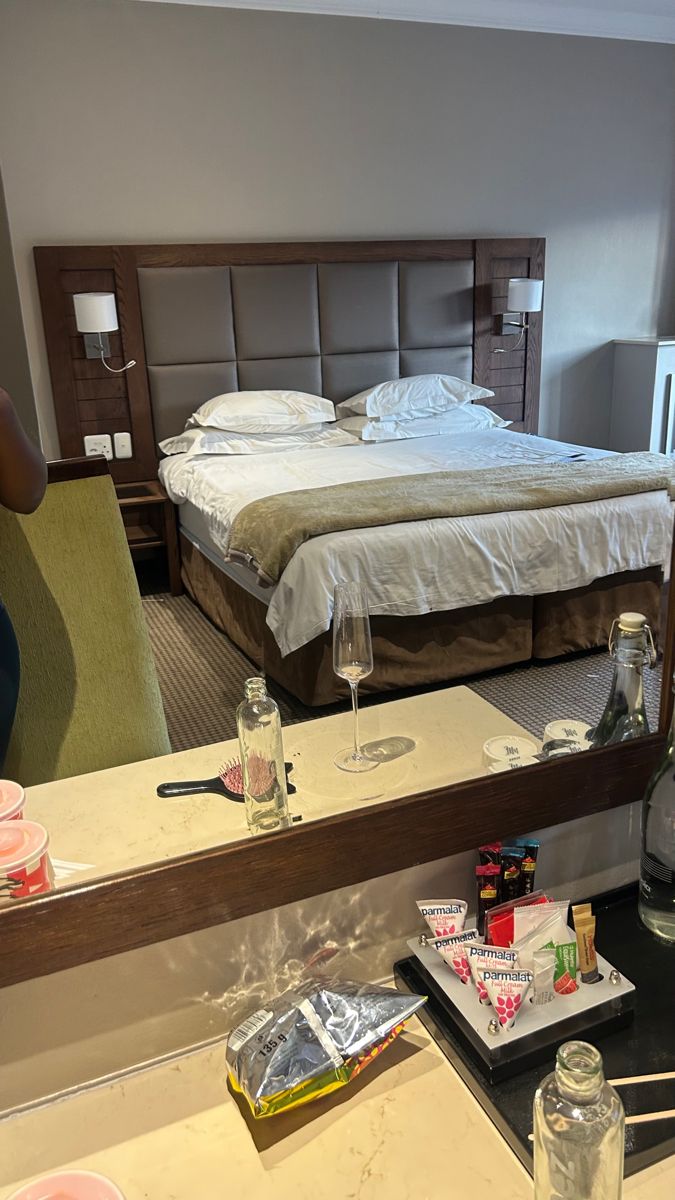 a hotel room with a bed, desk and chair in it's reflection on the mirror