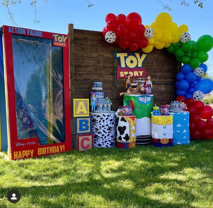 a toy story birthday party setup with balloons and games on the grass in front of it