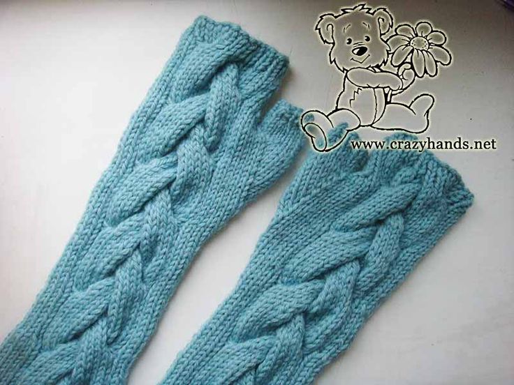 two blue knitted arm warmers sitting on top of a white table next to a teddy bear