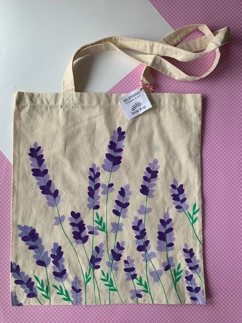 a tote bag with lavender flowers painted on it and a tag hanging from the front