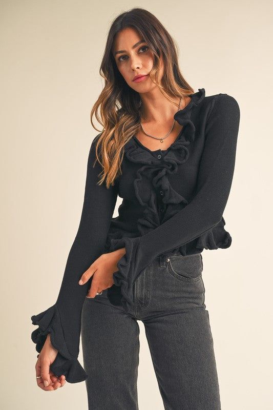 The Lila Ruffled cardigan sweater is a extra soft, stylish and sophisticated piece for any wardrobe. Constructed with a sweater knit top and a neckline detail front, the ruffle and frill sleeve creates a unique, dramatic effect. Long sleeve and button closure complete the design for a fashionable and comfortable look. 55% Acrylic 45% Rayon Ruffle Cardigan Outfit, Soft Dramatic Necklines, W2e Outfits, Ruffle Shirt Outfit, Ruffle Pants Outfit, Black Top Outfit, Black Ruffle Top, Ruffle Outfit, Ruffle Cardigan