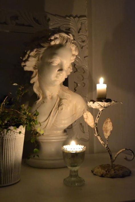 a white statue sitting next to a candle on top of a table