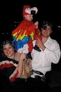 a man holding a woman in his arms and a parrot on her shoulder at night