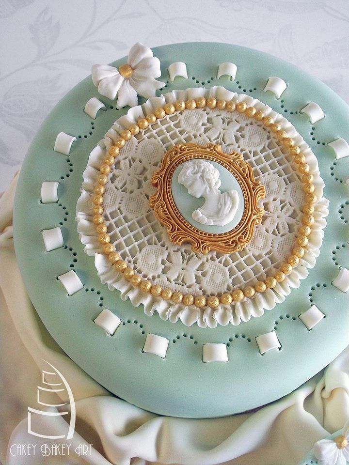 there is a cake decorated with white and gold decorations on top of a blue plate