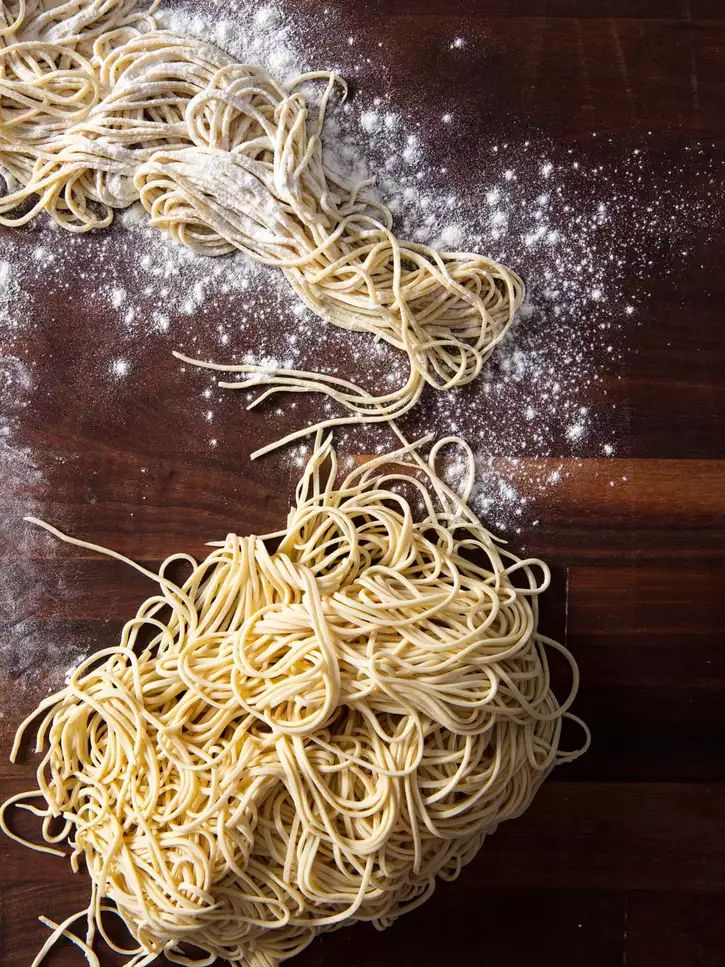 some noodles are sprinkled with flour on a wooden table