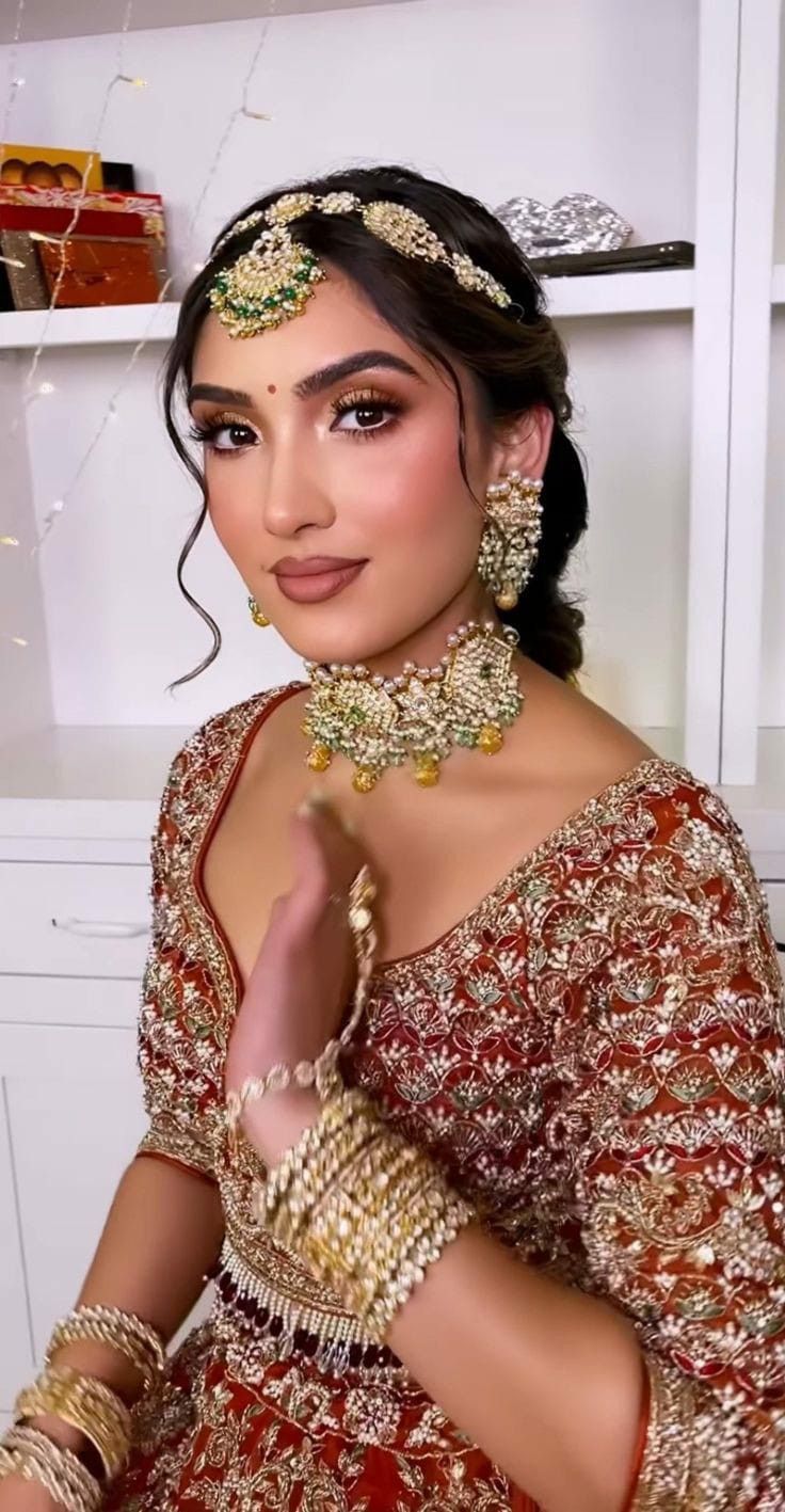 a woman in a red and gold outfit with jewelry on her head, posing for the camera