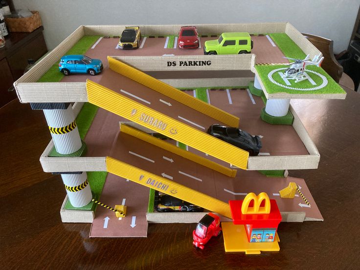 a toy car park with cars and trucks on the play set, including a parking garage