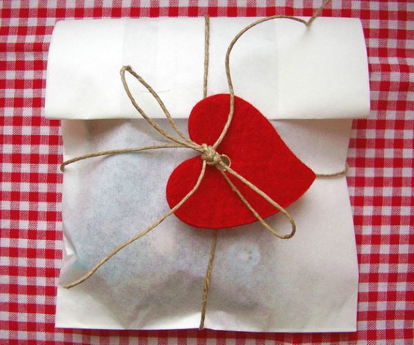 an envelope with a red heart tied to it on a checkered tablecloth background