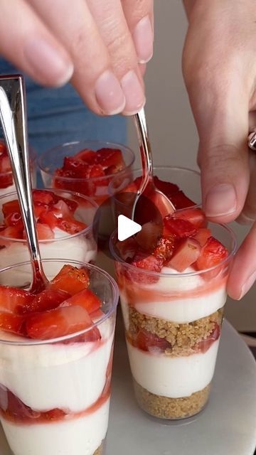 someone is spooning strawberries into small desserts