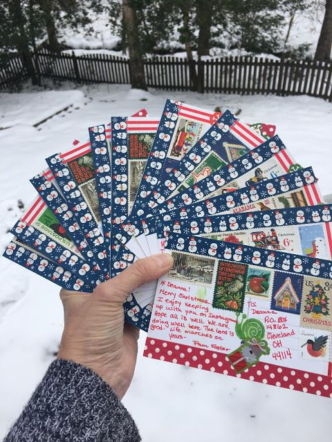 someone holding up some christmas cards in the snow with red, white and blue designs on them