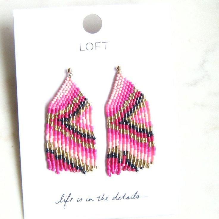 a pair of pink and black beaded earrings sitting on top of a white card