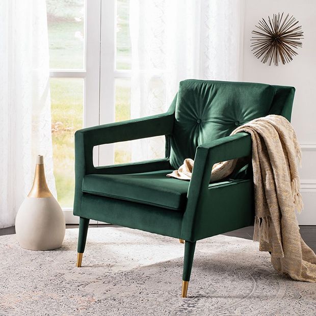 a green chair sitting on top of a white rug next to a vase and window