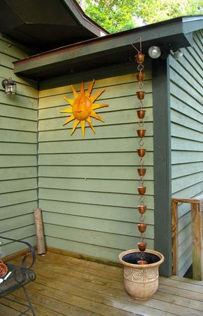 a sun decoration hanging from the side of a house on a porch with a potted plant