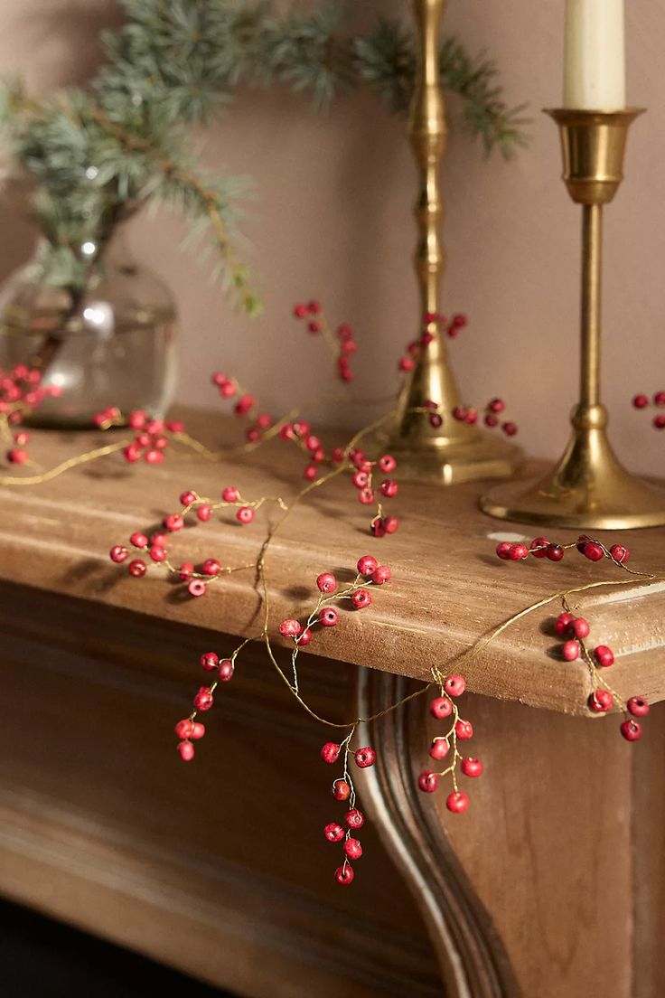 a mantle with candles and red berries on it